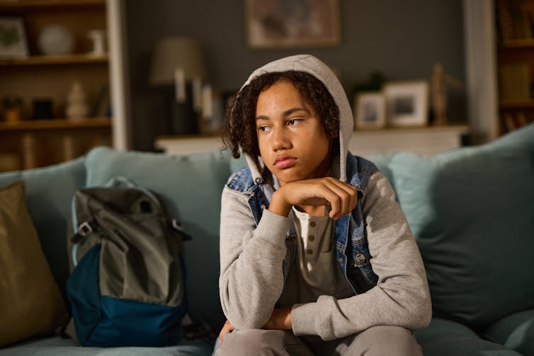 Teen sits on sofa looking stressed