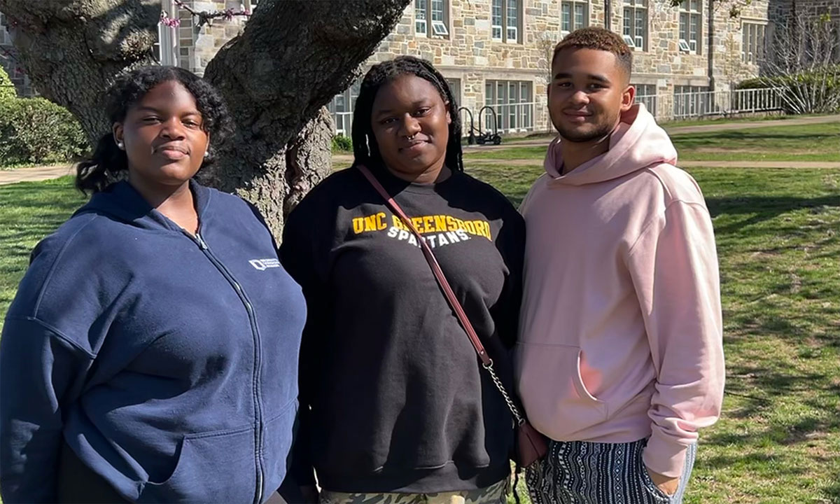 A photo of three students standing outside of their school in Washington, D.C.